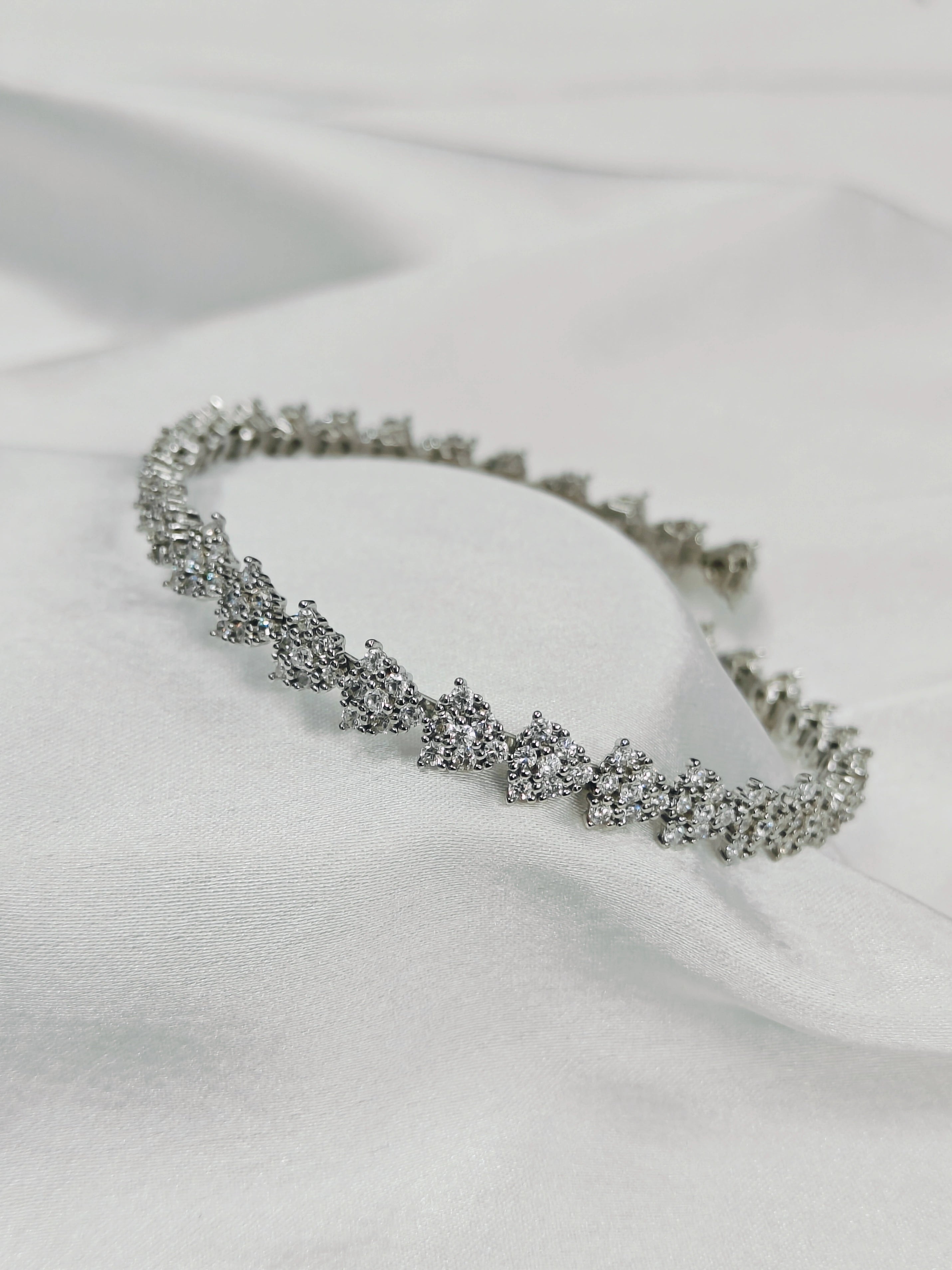 Silver bracelet with clear stones on a white fabric background